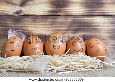 Five brown eggs with funny faces on wooden background