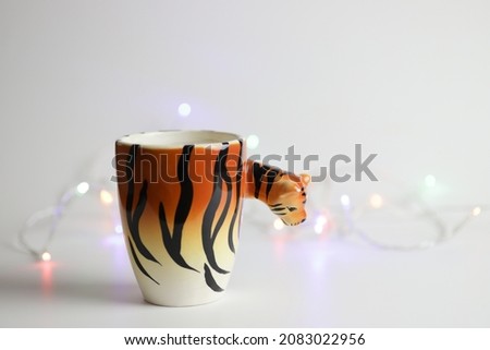 Mug with print of tiger with Christmas lights on background. High quality photo