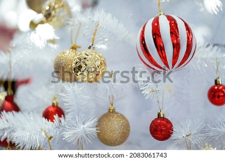CLOSE UP CHRISTMAS ORNAMENT WITH WHITE AND RED STRIBE , RED, GOLD BALL-COLOR ON THE WHITE CHRISTMAS TREE THEME.