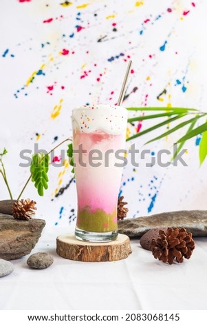 Minimalist Concept Idea. Avocado ice milk summer drink on wood with green leaves and stones on abstract background.
