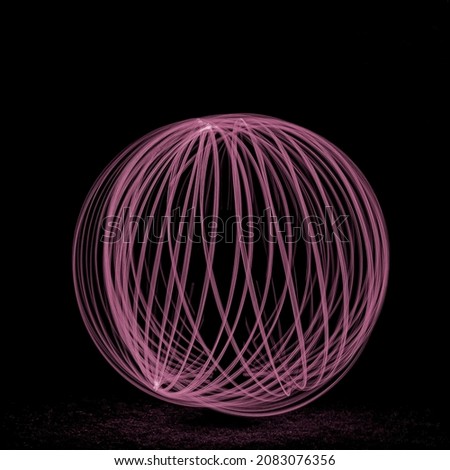 Light painting of a ball shape resulting in an pink glow against a black background