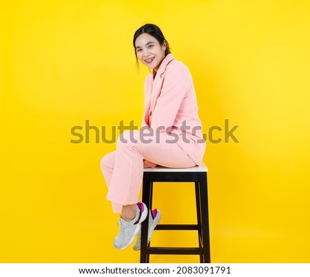 Naughty Asian girl on pink pastel jacket and pants sit leisurely on high chair posing model character for adult costume fashion. Relaxing portrait for modern clothing and suit for female outfit.