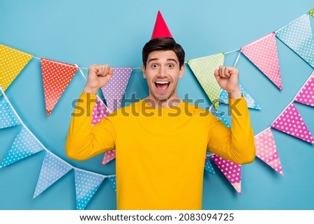 Photo of ecstatic guy celebrate birthday raise fists enjoy gifts isolated over blue color background