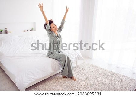 Full size photo of young attractive woman sit bed arms up stretching wear silky pajama ready for new day indoors
