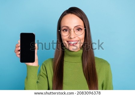 Photo of funny sweet mature lady dressed green turtleneck spectacles holding modern gadget empty space isolated blue color background
