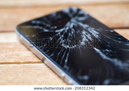 Broken glass of smart phone on the wood table. Selective focus. Royalty-Free Stock Photo #208312342