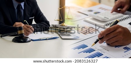 Hand holding a pen, pointing to a graph, pressing a calculator to analyze financial calculations, and lawyers work with hammer scales on the table financial approval ideas. Royalty-Free Stock Photo #2083126327