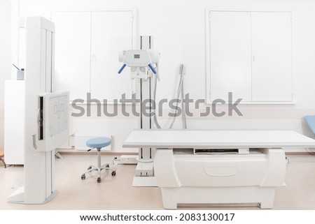 X-ray department in modern hospital. Radiology room with scan machine with empty bed. Technician adjusting an x-ray machine. Scanning chest, heart, lungs in modern clinic office. Royalty-Free Stock Photo #2083130017