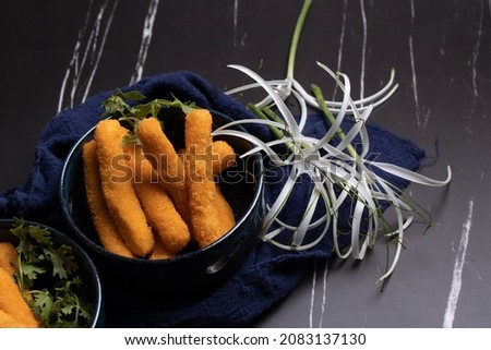 Chicken nuggets sticks in a cup on black background.