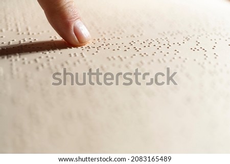 a finger following the reading of a page written in the Braille alphabet. Royalty-Free Stock Photo #2083165489