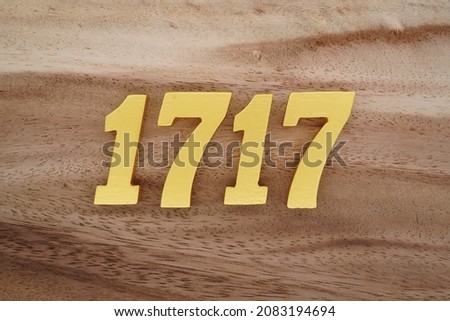 Golden Arabic numerals 1717 on a dark brown to white wood grain background.