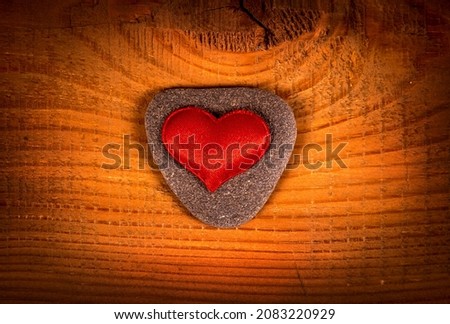 Vignetting Photo of Red Heart Shape on a Pebble and Wooden Planks Background closeup