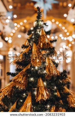 Creative Christmas tree decorated with gold Christmas toys. Festive atmosphere and shiny decorations in the interior with bokeh lights