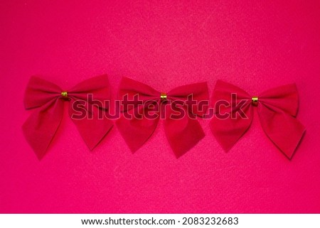 Three red bows in a row with a gold thread on a red background