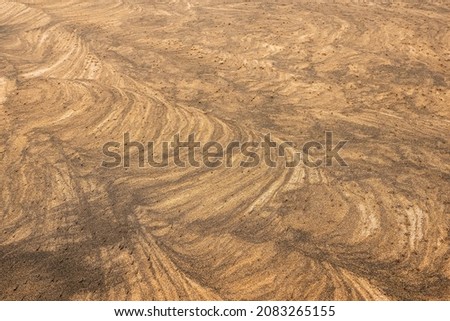 Amazing natural sand pattern made by wind and water on a sandy beach. Unique design for creative purpose. Design background. Random shapes on a dark and light sand surface