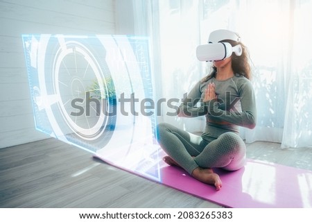 The Hispanic woman wearing VR goggles and doing Yoga and dancing at home, the concept of metaverse, versual really, activity, cyberspace and future Royalty-Free Stock Photo #2083265383