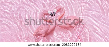 Trendy summer composition with two pink flamingos forming a heart in water pink background. Valentine's day concept
