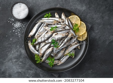 Sardines with lemon, salt and parsley close-up on a dark background. Sea fish. Top view. Royalty-Free Stock Photo #2083277104