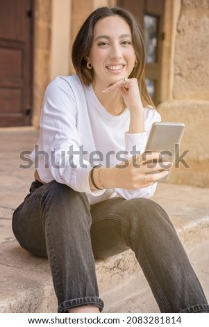 young woman looking at camera with mobile phone outdoor city life
