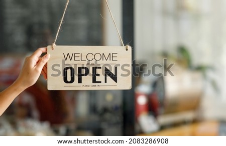 Close up of hand, Store owner turning open sign broad through the door glass and ready to serve.