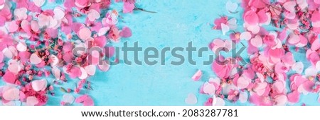 Valentine day panorama with a frame of pink hearts and flowers confetti, a panoramic frame on a blue background with copy space