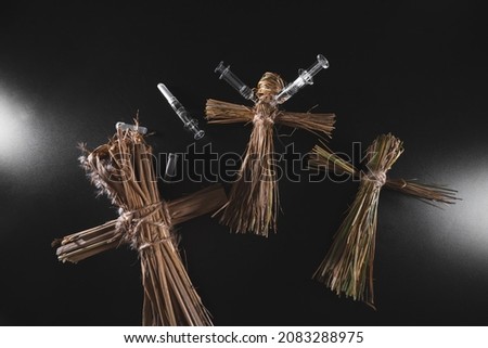 Voodoo doll and syringes on a black background. People management concept. Compulsory vaccination. Drugs and Medicine. Ritual and conspiracy