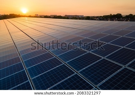 Blue photovoltaic solar panels mounted on building roof for producing clean ecological electricity at sunset. Production of renewable energy concept. Royalty-Free Stock Photo #2083321297