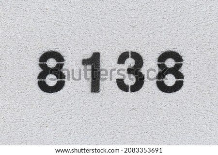 Black Number 8138 on the white wall. Spray paint. Number eight thousand one hundred thirty eight.