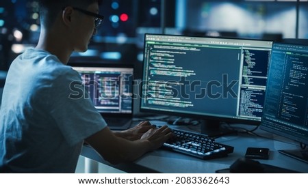 Night Office: Young Handsome Man in Working on Desktop Computer. Digital Entrepreneur Typing Code, Developing Modern Software, e-Commerce App Design, Developing of e-Business. Over Shoulder Royalty-Free Stock Photo #2083362643