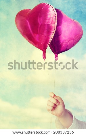 balloons in child hands against the sky