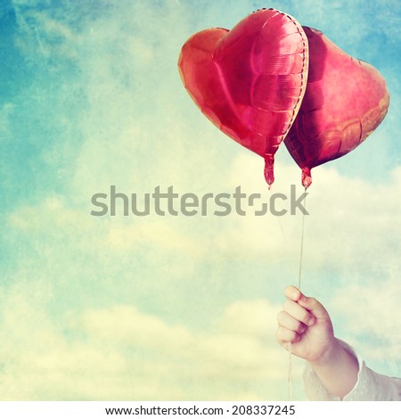 balloons in child hands against the sky