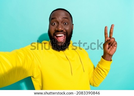 Photo of brunette cool young beard guy do selfie show v-sign wear yellow sports cloth isolated on teal color background