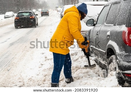 a driver with a shovel removes snow next to the car. background picture.