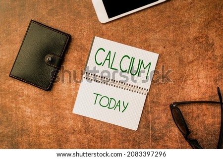 Conceptual caption Calcium. Conceptual photo fifth most abundant element in the human body Silverwhite metal Wooden Desktable With Smartphone Leather Wallet Eyeglasses And Notepad
