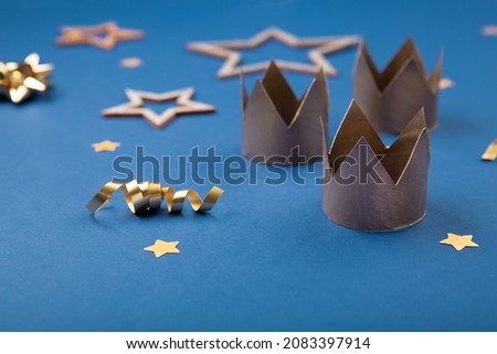 Traditional Three King's Day of January 6. Three gold crowns on blue background with winter decorations. Happy Epiphany day. Selective focus, copy space.
