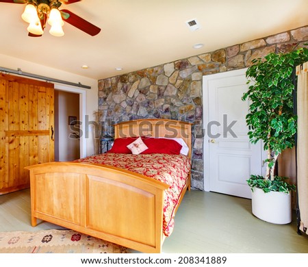 Exotic bedroom interior with stone wall trim, wooden bed and decorative tree in corner