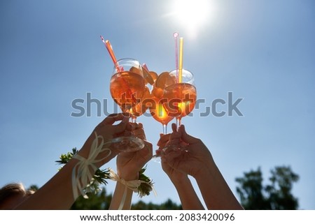 Women hands toasting with aperol spritz cocktails on summer party on blue sky background, copy space. Event celebration concept. Traditioanal italian aperitif. Royalty-Free Stock Photo #2083420096