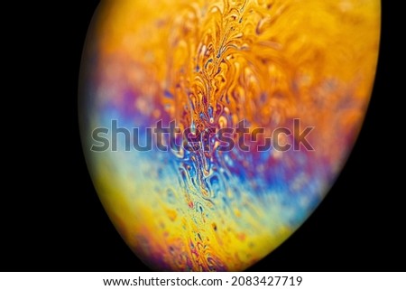 Extreme closeup soap bubble, like multicolor abstract round alien planet in universe on dark background