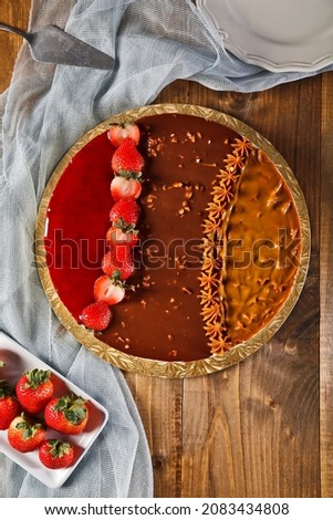 Birthday cheesecake in chocolate with nuts strawberries on wood background. Picture for a menu or a catalog.
