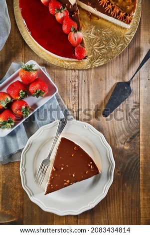 Birthday cheesecake in chocolate with nuts strawberries on wood background. Picture for a menu or a catalog.
