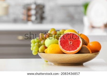 Plate with different fruits on kitchen table Royalty-Free Stock Photo #2083436857