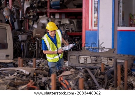 A mechanic or a foreman is checking the stock of used car parts in a warehouse. 