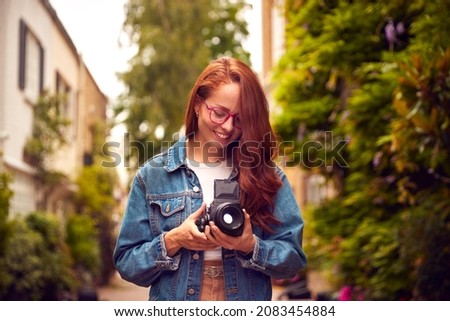 Young Woman In City Taking Photo On Retro Medium Format Film Camera To Post To Social Media