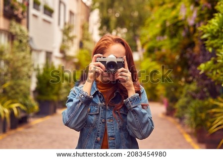 Young Woman In City Taking Photo On Digital Camera To Post To Social Media