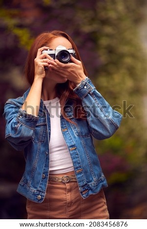 Young Woman In City Taking Photo On Digital Camera To Post To Social Media