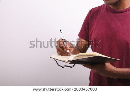 an African American is writing on a notebook you can only see his upper body