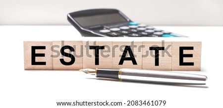 The light table has a black calculator, a fountain pen, and wooden cubes with the text ESTATE. Business concept