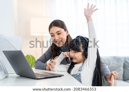 Asian little young girl kid learning online class at home with mother. Preschool child use laptop computer do homework, homeschool from school teacher by digital remote internet with support from mom. Royalty-Free Stock Photo #2083466353