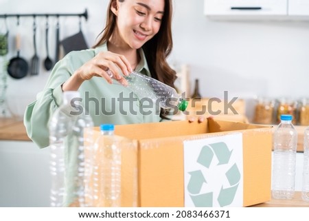 Asian beautiful woman separating trash for further recycling at home. Attractive female put plastic bottles into recycle box for ecologically friendly and saving the environment. Zero waste concept.