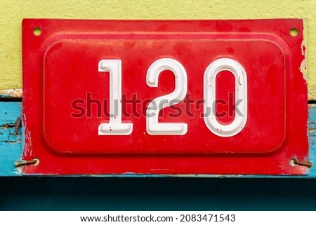 Door number on the wall, white numbers on red plate, 120, retro